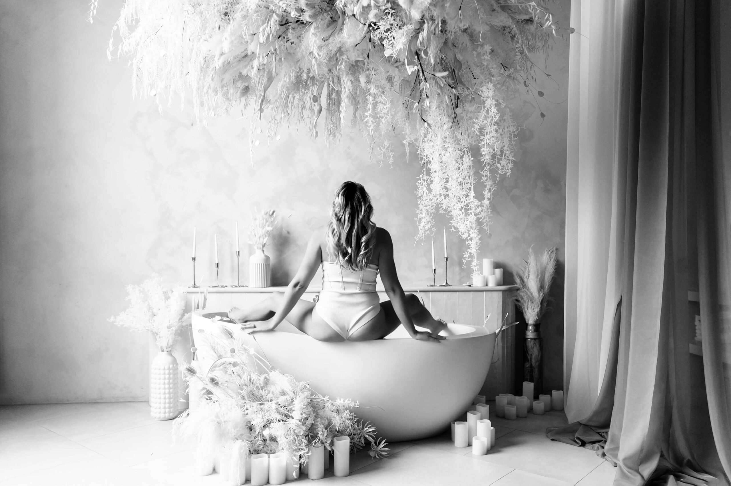 black and white photo of a woman sitting on a tub with her legs ups for her Ontario Boudoir Photography Session.