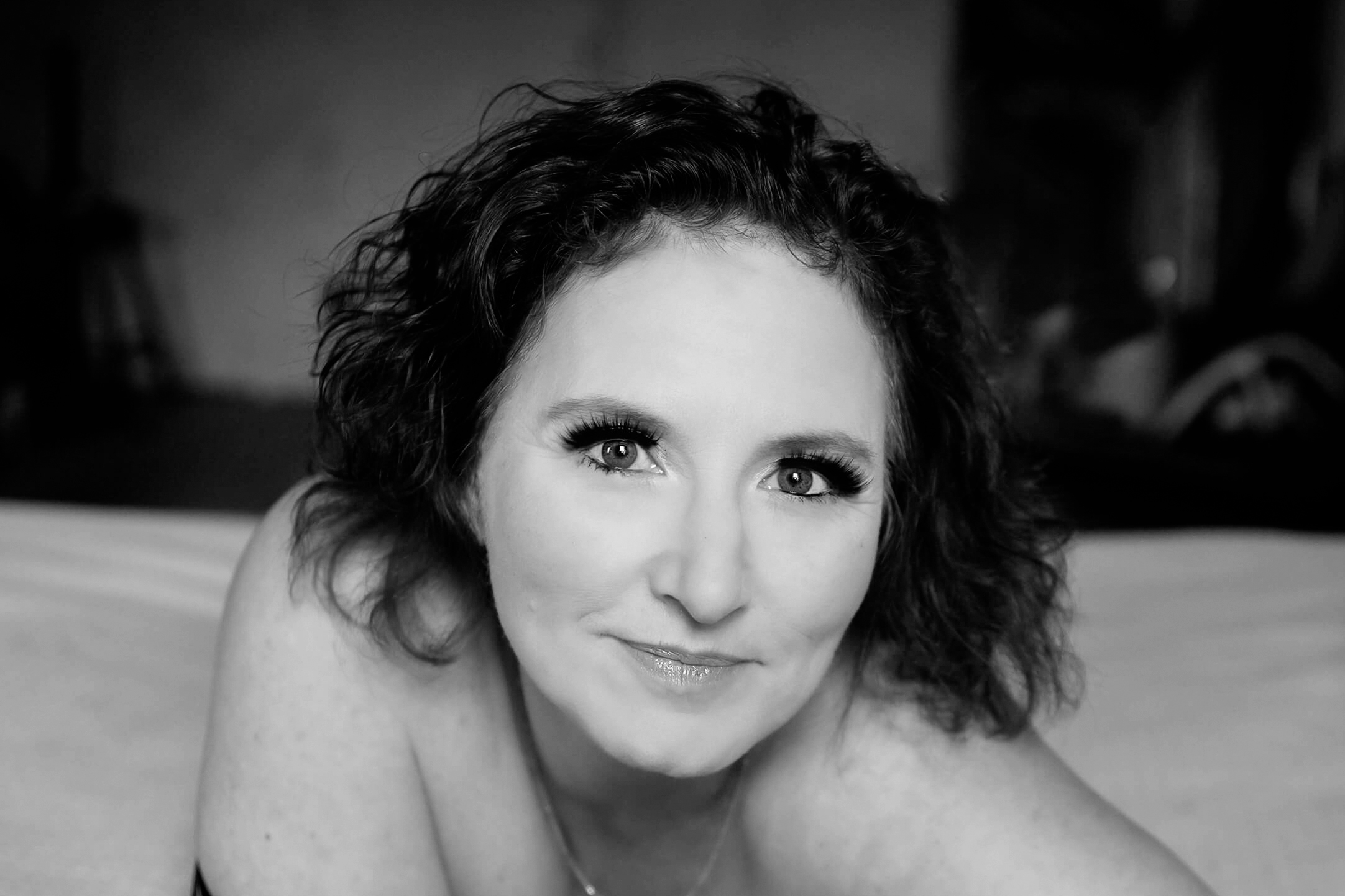 Black and white photo of a woman with curly hair staring into the camera with her Toronto Eyelash Extensions.