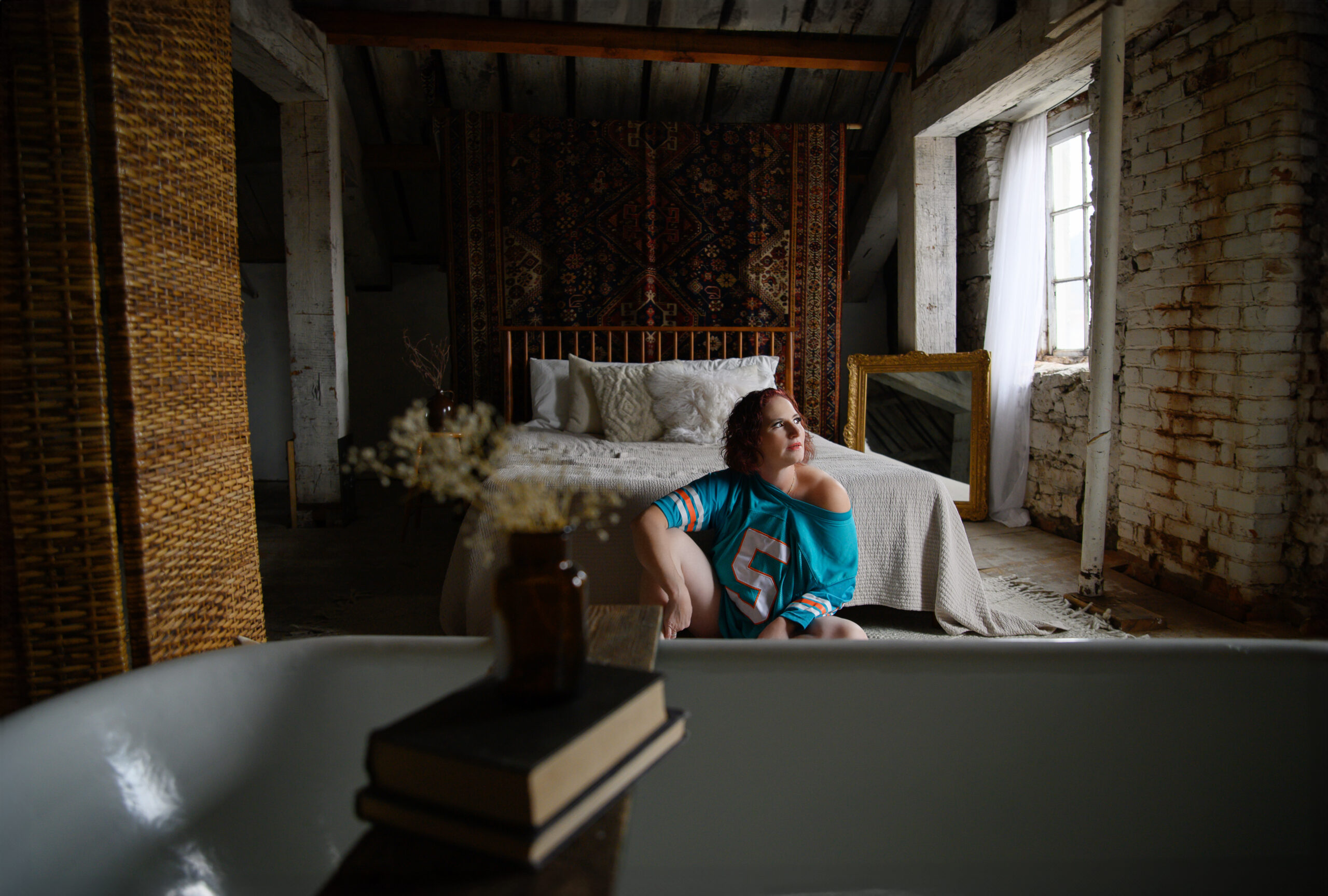 Red haired woman sitting with a Miami Jersey on a floor for her Hamilton luxury boudoir photography session.