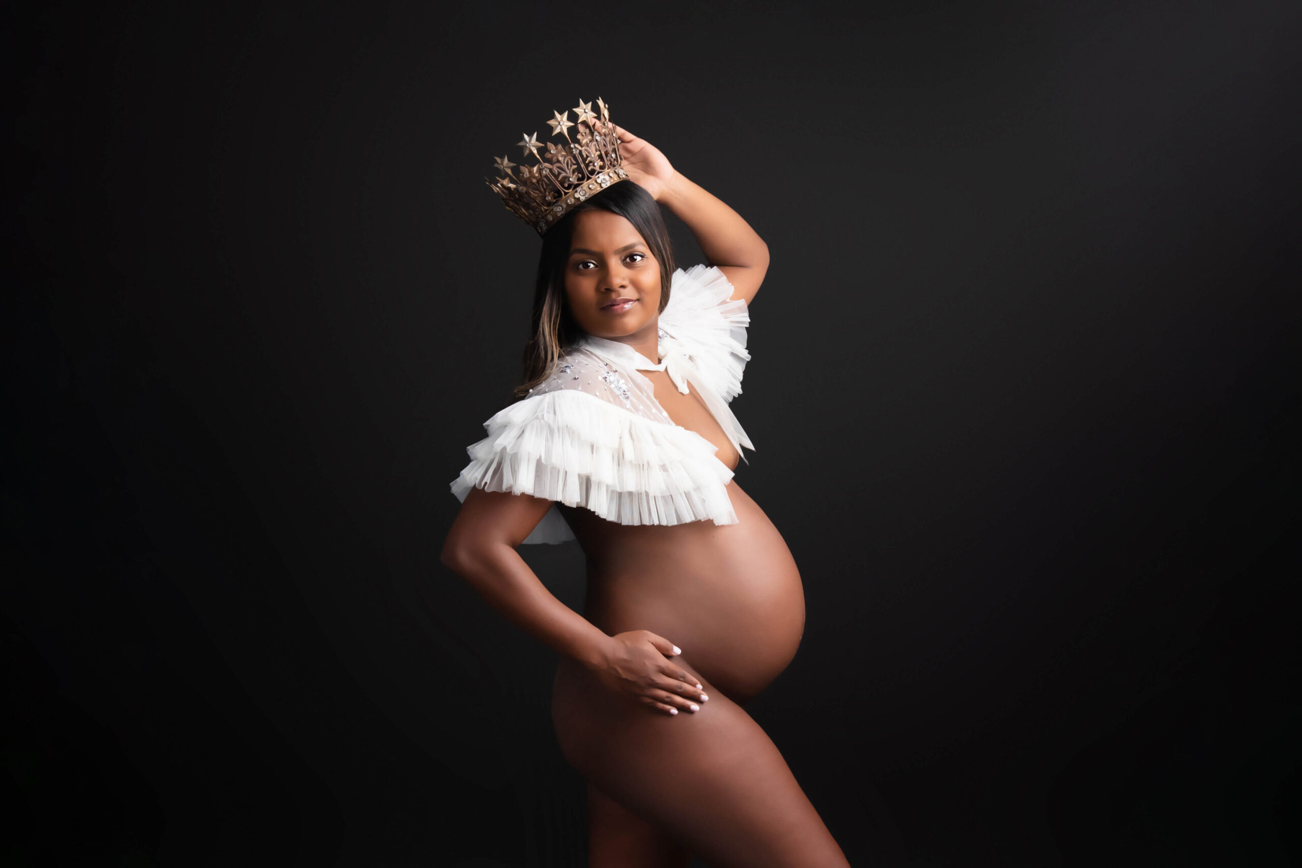 African American pregnant woman wearing a white bolero and gold crown for her Boudoir Maternity Photography Session Toronto Ontario.