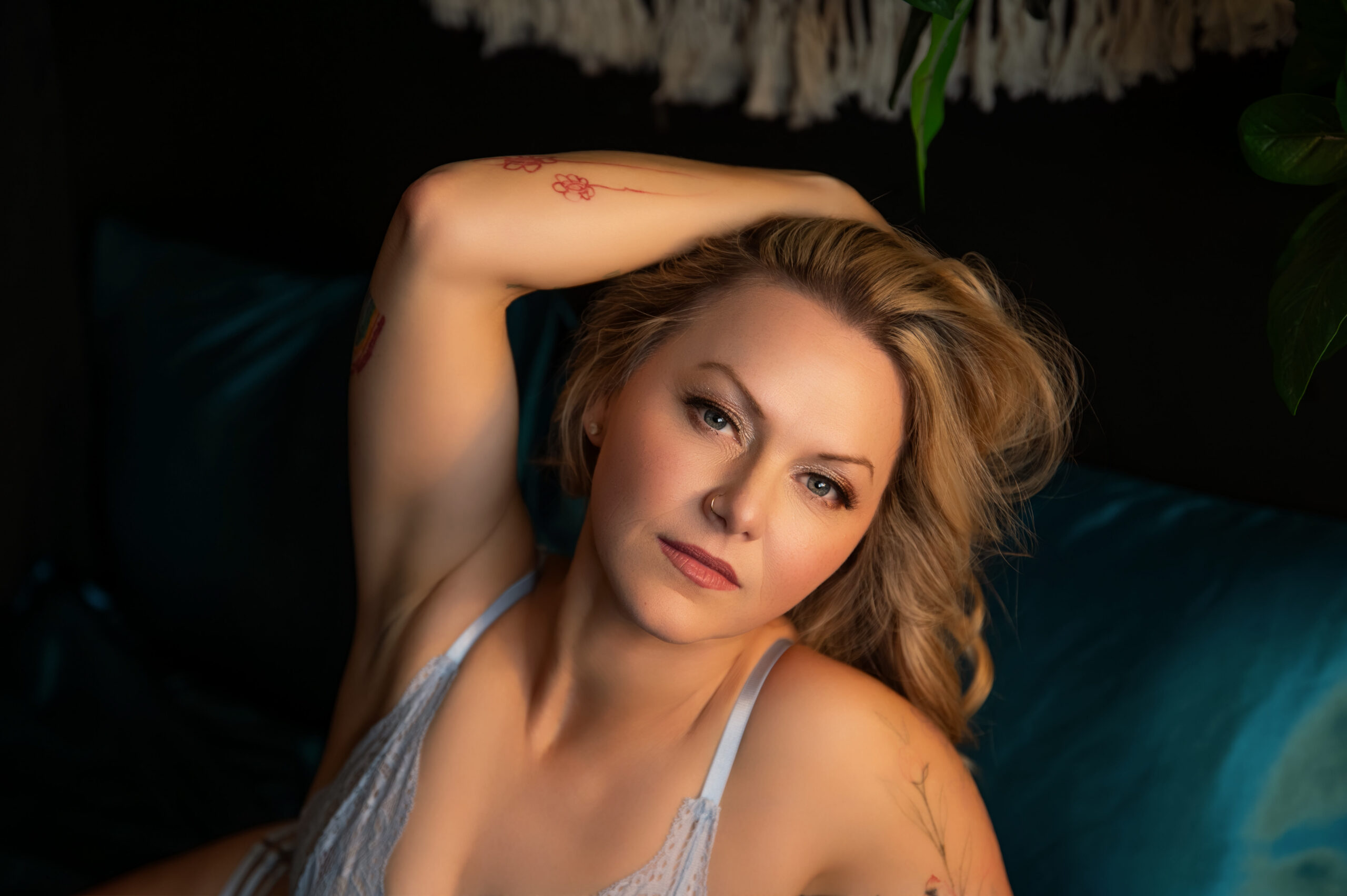 natural makeup on a blonde haired woman sitting on a bed for her Burlington boudoir photos.